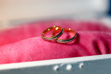 A close-up shot of expensive gold wedding rings on pink pillow. Gold Wedding rings on a pillow on pink