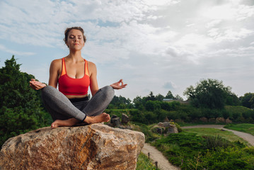 Sitting and meditating. Dark-haired slim and healthy woman sitting and meditating while having vacation