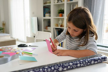 Cute little school girl writing birthday cards