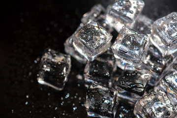 Top view of ice cubes reflection on black table background. Pile of different ice cubes on reflection black background.