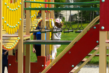 Little children run around and play in the playground. Game center for a young child. Little girl is playing outdoors. The concept of summer children's entertainment.