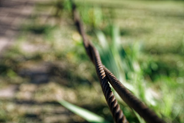Thick steel rope close up. Bridge fence element. Detailed view. The surface of the steel cable is covered with rust.