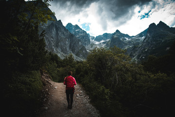 Female with red backpack in dark mountains