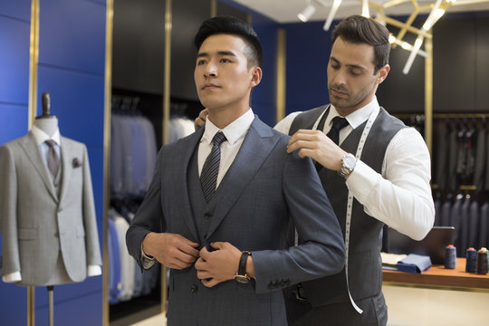 Fashion designer examining suit on customer