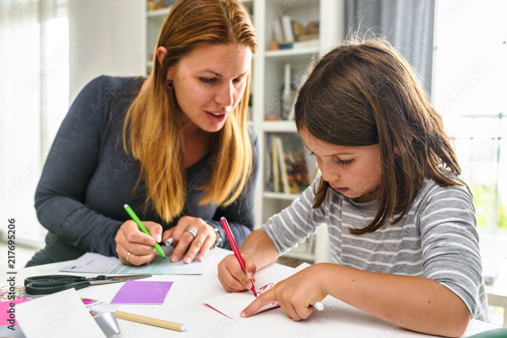 Wall mural Proud mother teaching child at home how to write. Early education