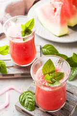 Fresh watermelon smoothie with ice and mint leaves in glasses.