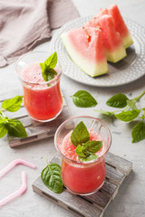 Fresh watermelon smoothie with ice and mint leaves in glasses.