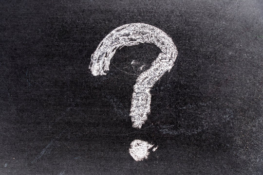 White color chak hand drawing in question mark shape on blackboard background