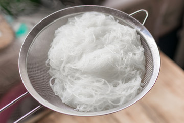 Boiled hot steaming rice noodles, spaghetti in a colander.