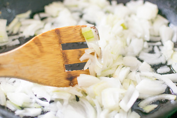 Fried onions in a frying pan. Roasting the chopped onion in oil.