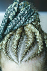 thick braids with interlacing of artificial material, colored synthetic hair, build-up, the girl is braided in a hairdress, the result of the work of the master