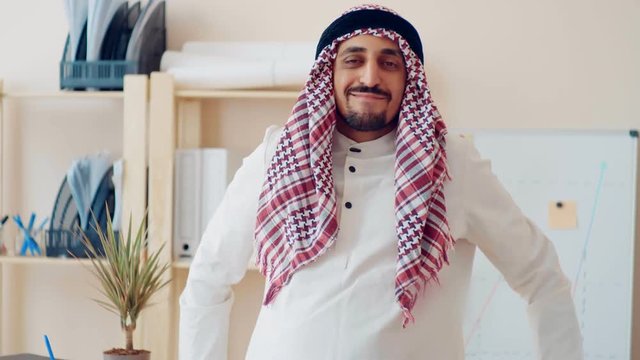 Handsome young muslim male in traditional Islamic clothing standing in front of financial chart painted on white board. work in the office