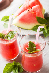 Fresh watermelon smoothie with ice and mint leaves in glasses.