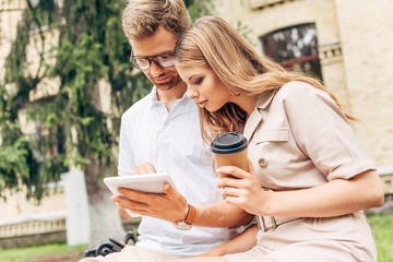 stylish young couple using tablet together near old building