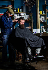 Barber with clipper trimming hair on nape of client. Hipster client getting haircut. Barber with hair clipper works on haircut of bearded guy barbershop background. Hipster hairstyle concept