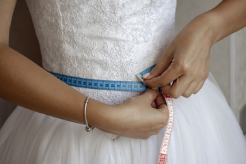 Bride measuring her waist before the wedding day