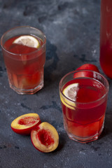 Two glasses of peach-raspberry lemonade with lemons and peaches on rustic background