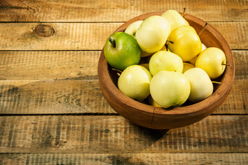 delicious green apples in a bowl on an old wooden table in the summer