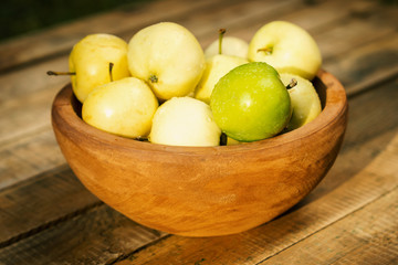 Fototapeta na wymiar delicious green apples in a bowl on an old wooden table in the summer
