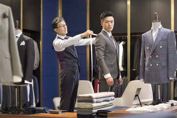 Fashion designer taking measurement of customer