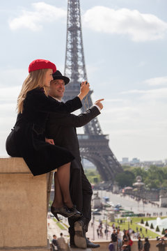 Happy Couple in Paris Taking Photo with Eiffel Tower Behind Them
