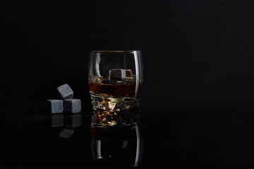 Irish whiskey. Glass of whisky with wiskey stones. Wiskey stones on black background. Elegant glass of whiskey