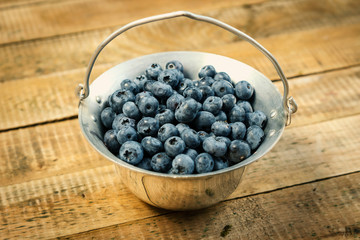 Juicy and blueberries in a container on an old wooden table in the summer