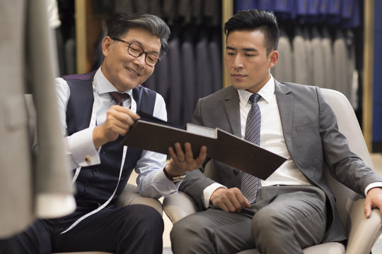 Fashion designer and customer talking in menswear shop