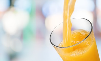 Orange juice pouring in glass on background
