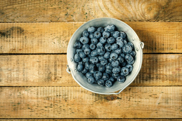 Juicy and blueberries in a container on an old wooden table in the summer