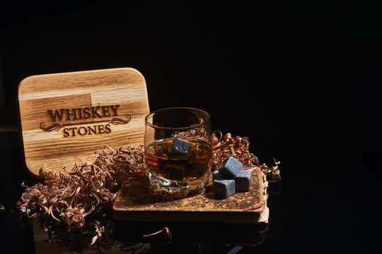 Irish whiskey. Glass of whisky with wiskey stones. Wiskey stones on black background. Elegant glass of whiskey . Whisky stones in wooden box