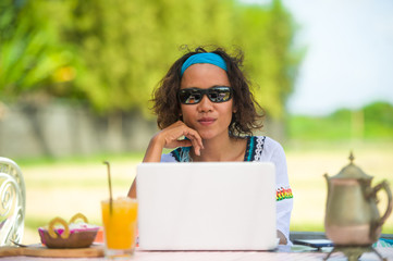 lifestyle outdoors portrait of young happy and attractive afro american mixed ethnicity woman working with laptop computer from beautiful cafe