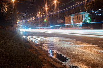 Fototapeta na wymiar Long exposure vehicle lights in city. Uneven light lines and reflection in a puddle. Editorial use only.