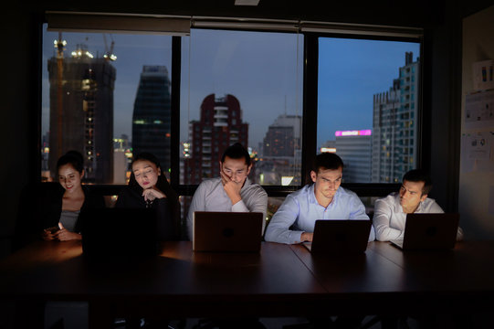 three businessman and two businesswoman working with computer overtime at night