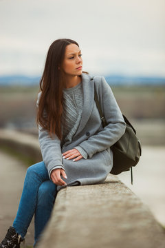 Young lonely and worried woman is sitting and looking at distance.