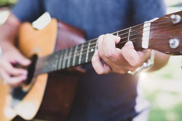 Fototapeta premium Close up of guitarist hand playing guitar. Musical and instrument concept. Outdoors and Leisure theme. Selective focus on left hand.