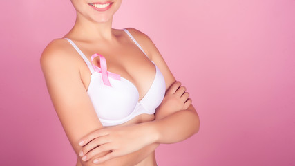 Side view of woman Breast Cancer Awareness ribbon standing against gray background