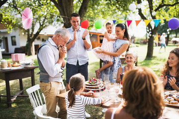 A senior man with an extended family looking at the birthday cake, crying.