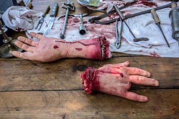 Realistic model of an amputated male hand lies on a dirty wooden table