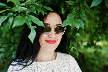 Brunette girl in white blouse with sunglasses posed at park.