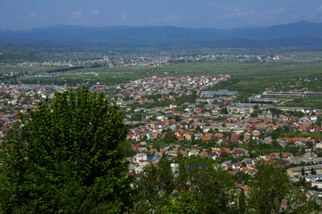 Colorful exalted view from a bird's eye view to houses in residential district in the city of Khust, Western Ukraine with high mountains in the background on a background of green vegetation.