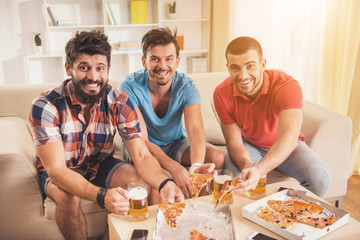 Young Smiling Men Drink Beer and Eat Pizza at Home