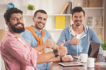 Obraz premium Three Young Smiling Men in Room with Laptop .