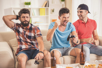 Three Young Happy Men Playing Video Games at Home.