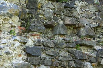 An old faded stone in the cracked weathered and shattered wall of a once majestic castle. In the category of creative background of exotic summer holidays, screen saver, wallpaper.