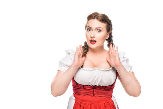 shocked oktoberfest waitress in traditional bavarian dress gesturing by hands isolated on white background