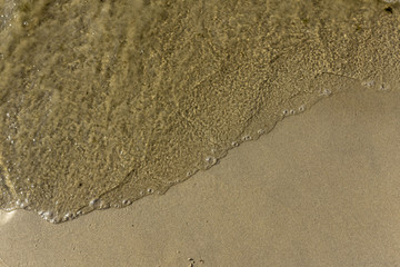 Sea wave and sand of the coastal beach. A good background for the site about the sea, love, romance, travel, nature, recreation.