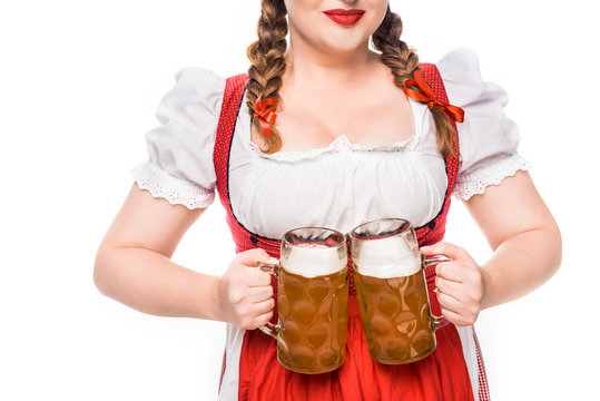 cropped image of oktoberfest waitress in traditional bavarian dress showing mugs of light beer isolated on white background