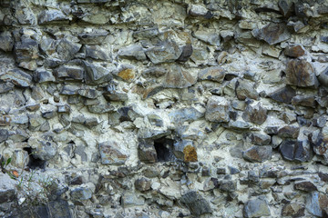 An old faded stone in the cracked weathered and shattered wall of a once majestic castle. In the category of creative background of exotic summer holidays, screen saver, wallpaper.