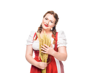 smiling oktoberfest waitress in traditional bavarian dress holding wheat ears isolated on white background
